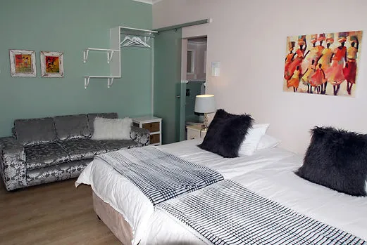 Bedroom with two beds sofa and artwork on pastelcolored walls