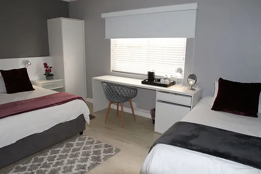 Modern hotel room with two beds desk chair and window blinds