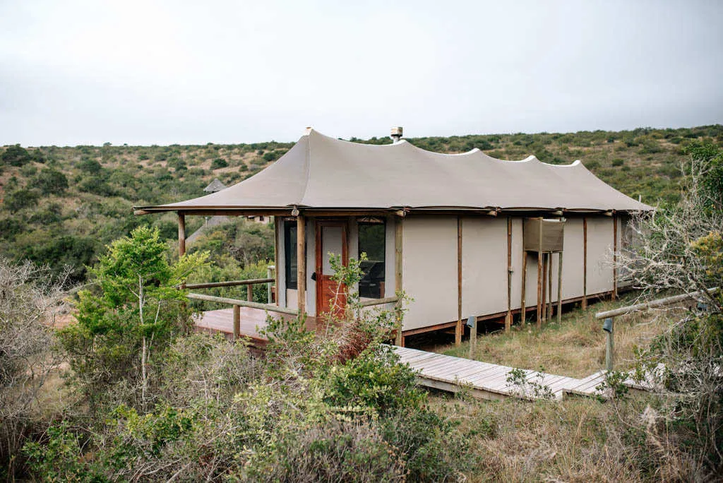 Tentstyle cabin with wooden deck in a natural hilly landscape