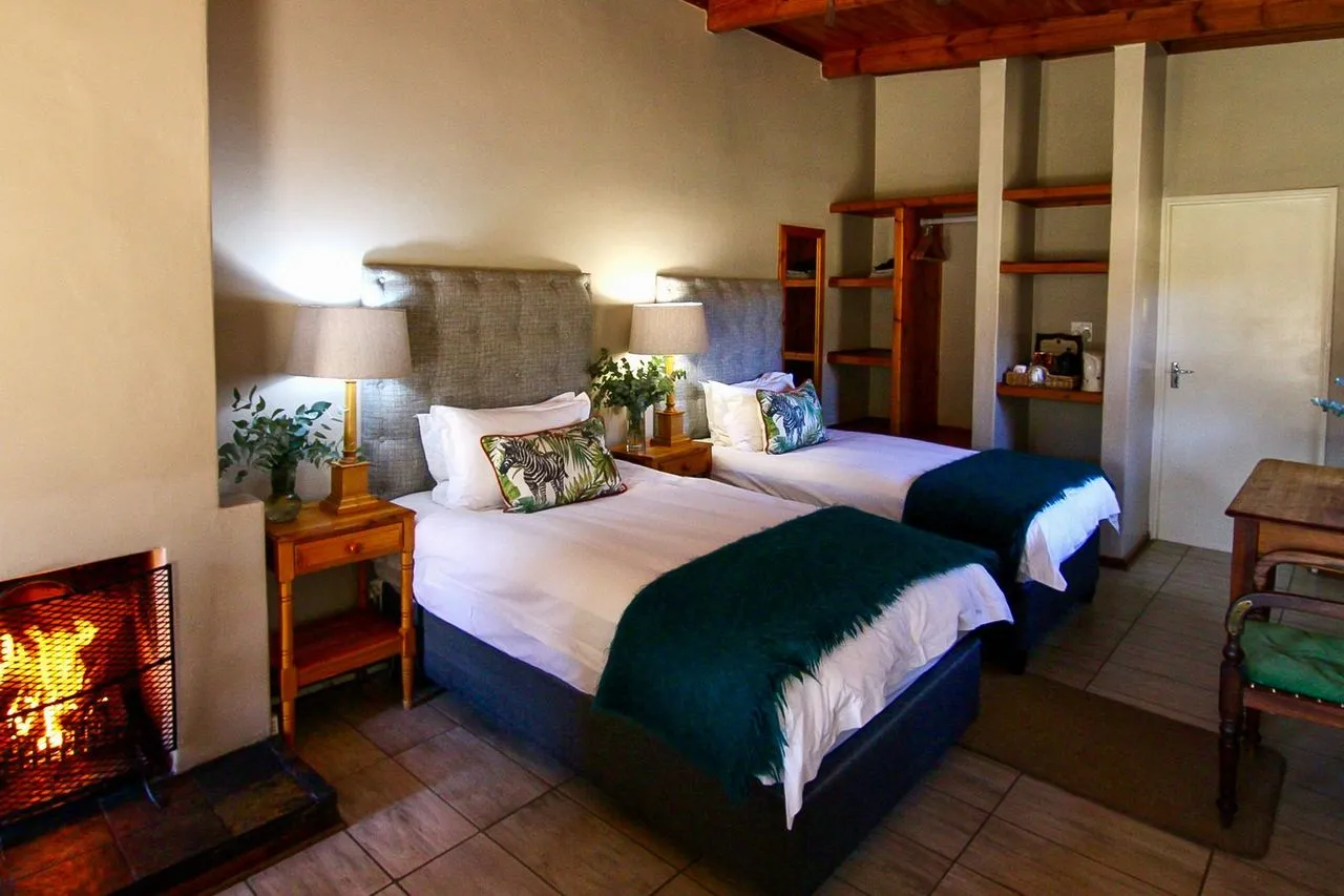 Two beds in a cozy bedroom with a fireplace and wooden furniture