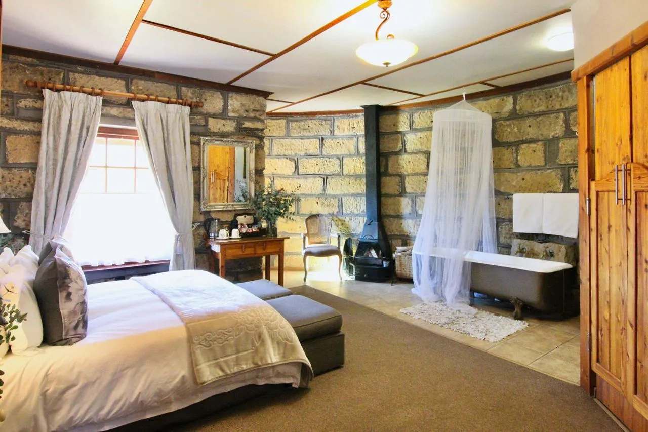 Cozy bedroom with stone walls large bed and a bathtub behind a curtain