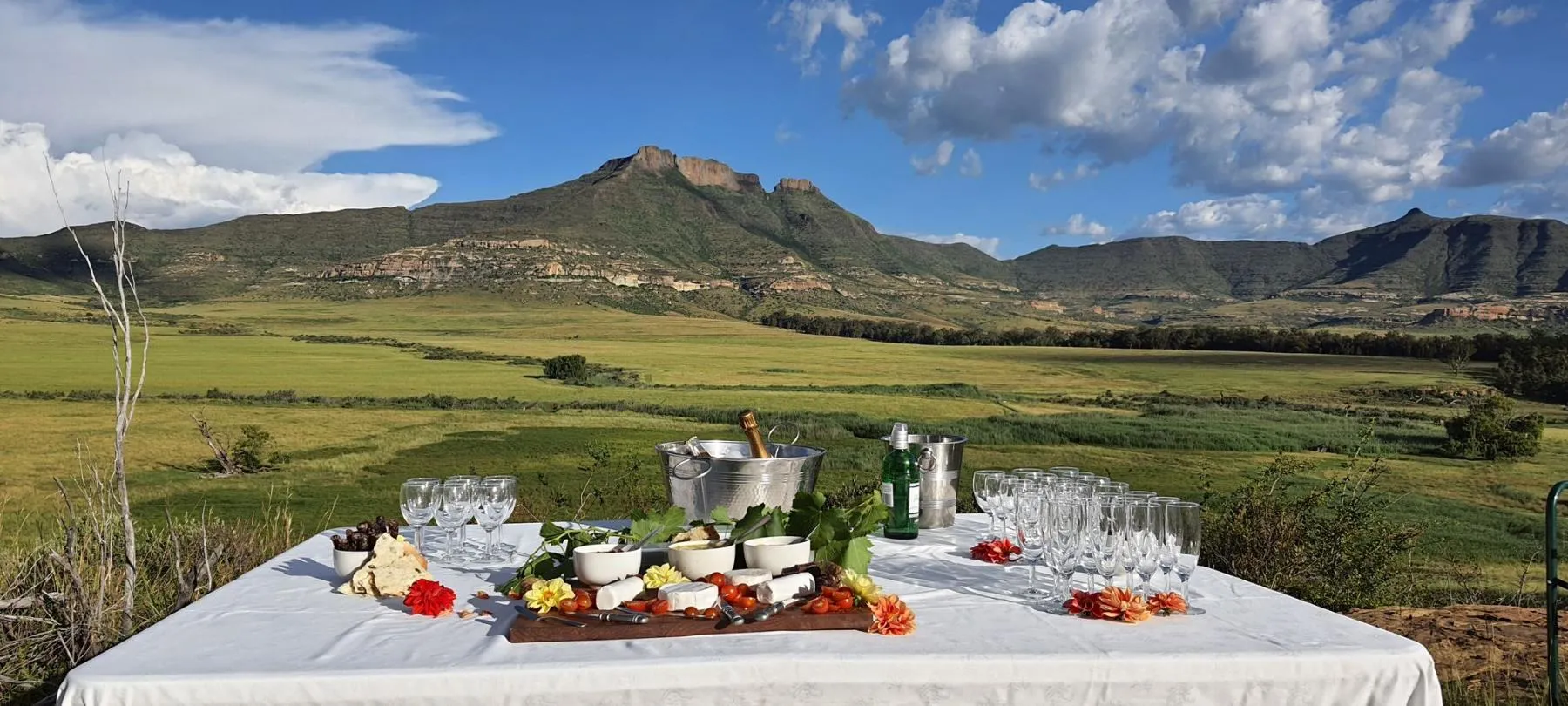 Outdoor table setup with food and wine glasses scenic mountain landscape in background