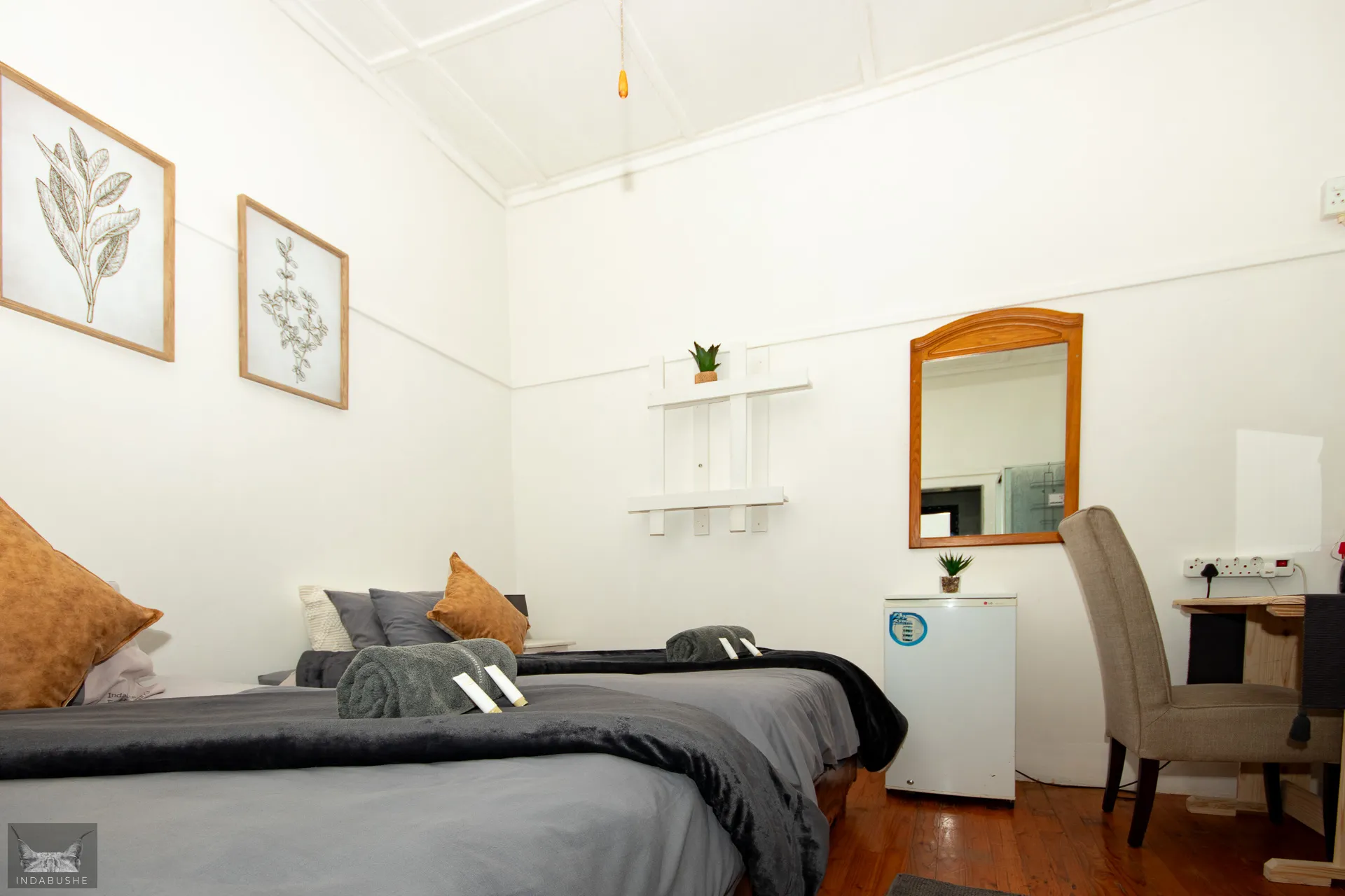 Cozy bedroom with two beds wall art mirror and small fridge