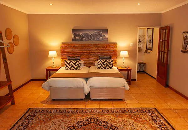 Twin beds in a cozy bedroom with wooden decor and an elephant picture