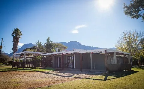 Singlestory house with verandas palm trees and mountains in the background