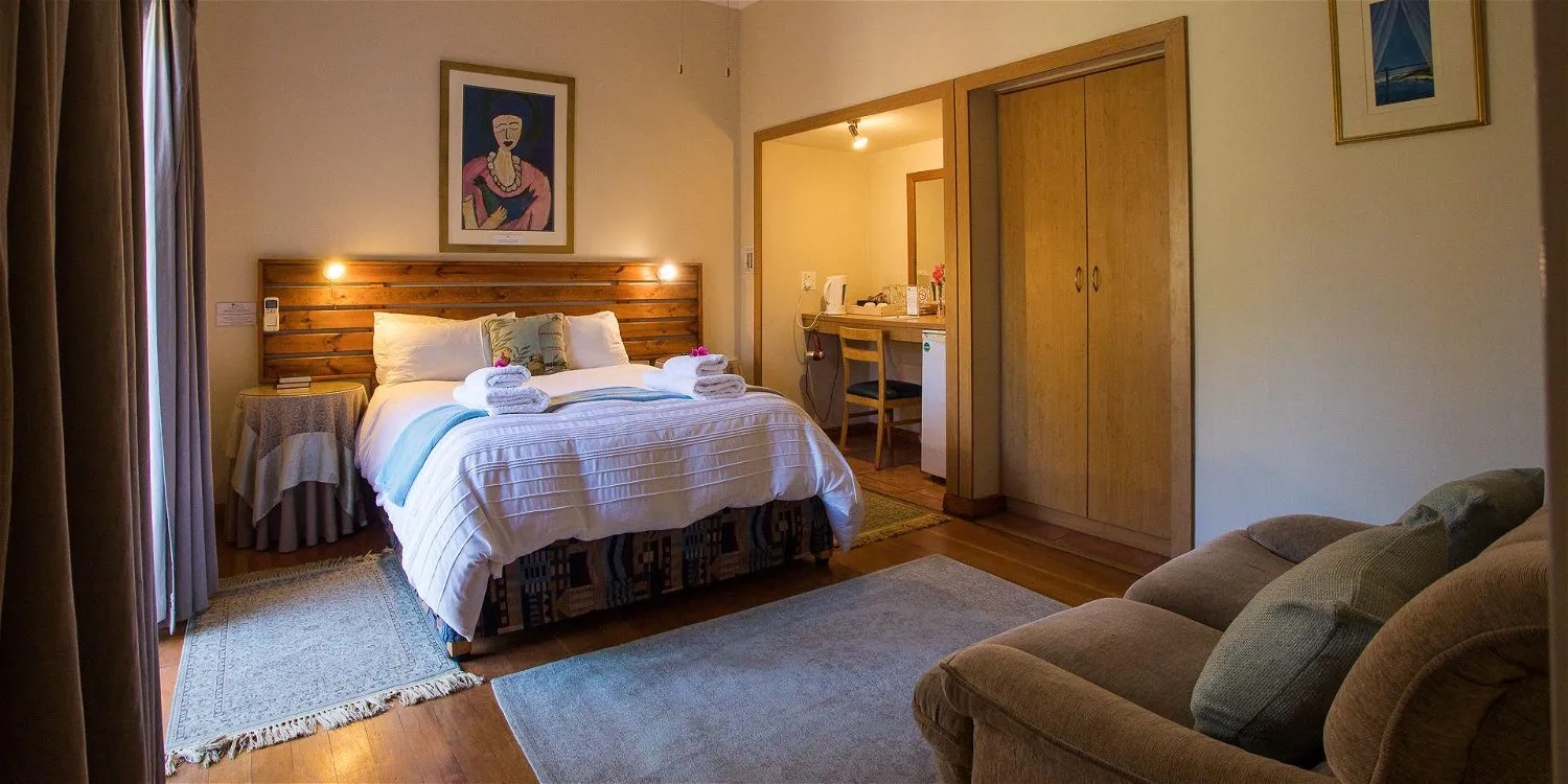 Cozy bedroom with a large bed wooden wardrobe and a comfortable sofa