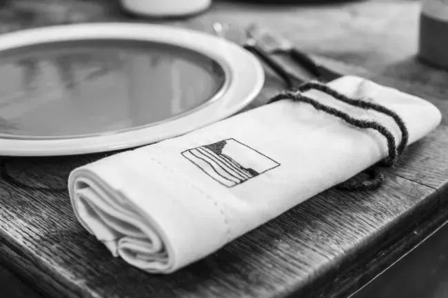 Rolled napkin with a string on a wooden table next to a plate