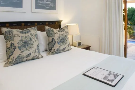 Neatly made bed with floral pillows in a bright bedroom with open door