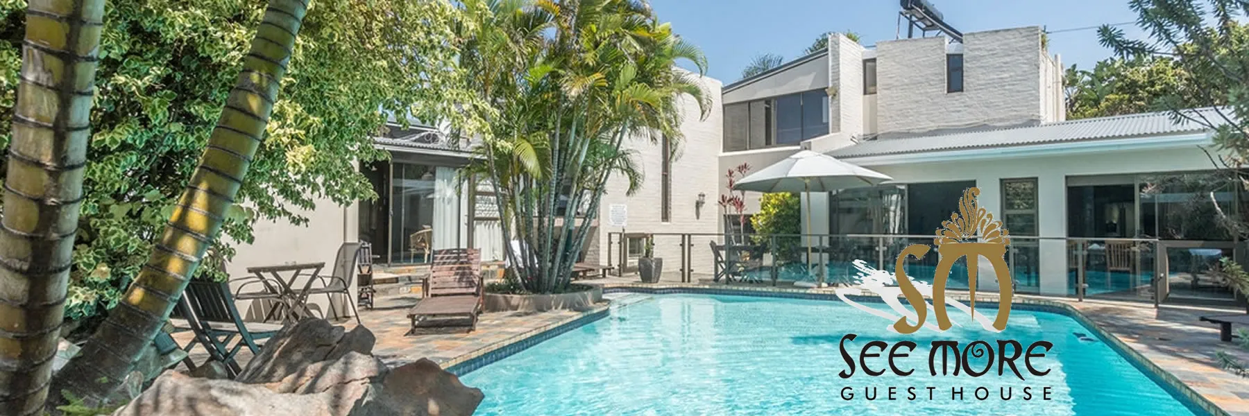 Modern guesthouse with pool palm trees and lounge chairs in a sunny setting
