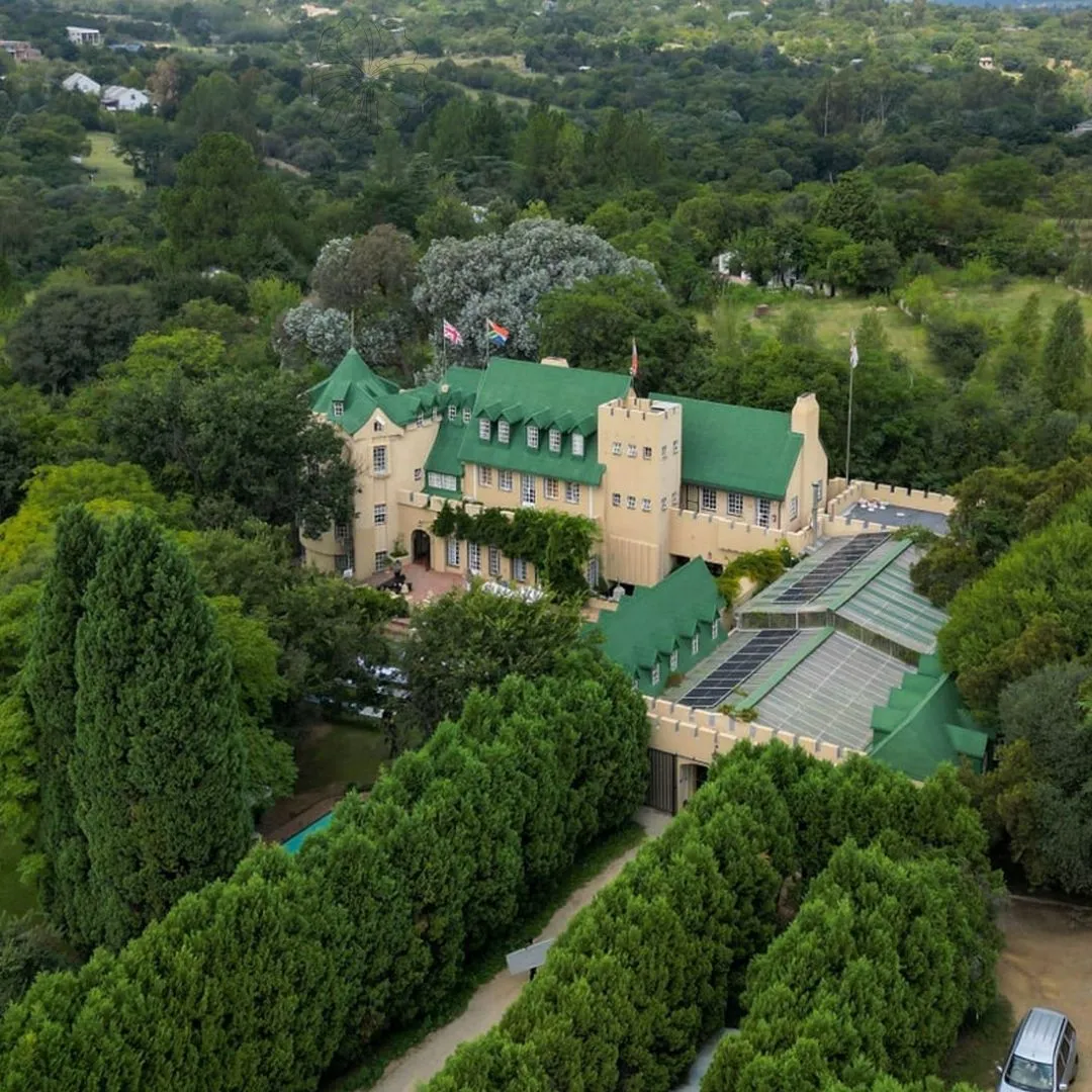 Large mansion with green roofs surrounded by lush greenery and trees