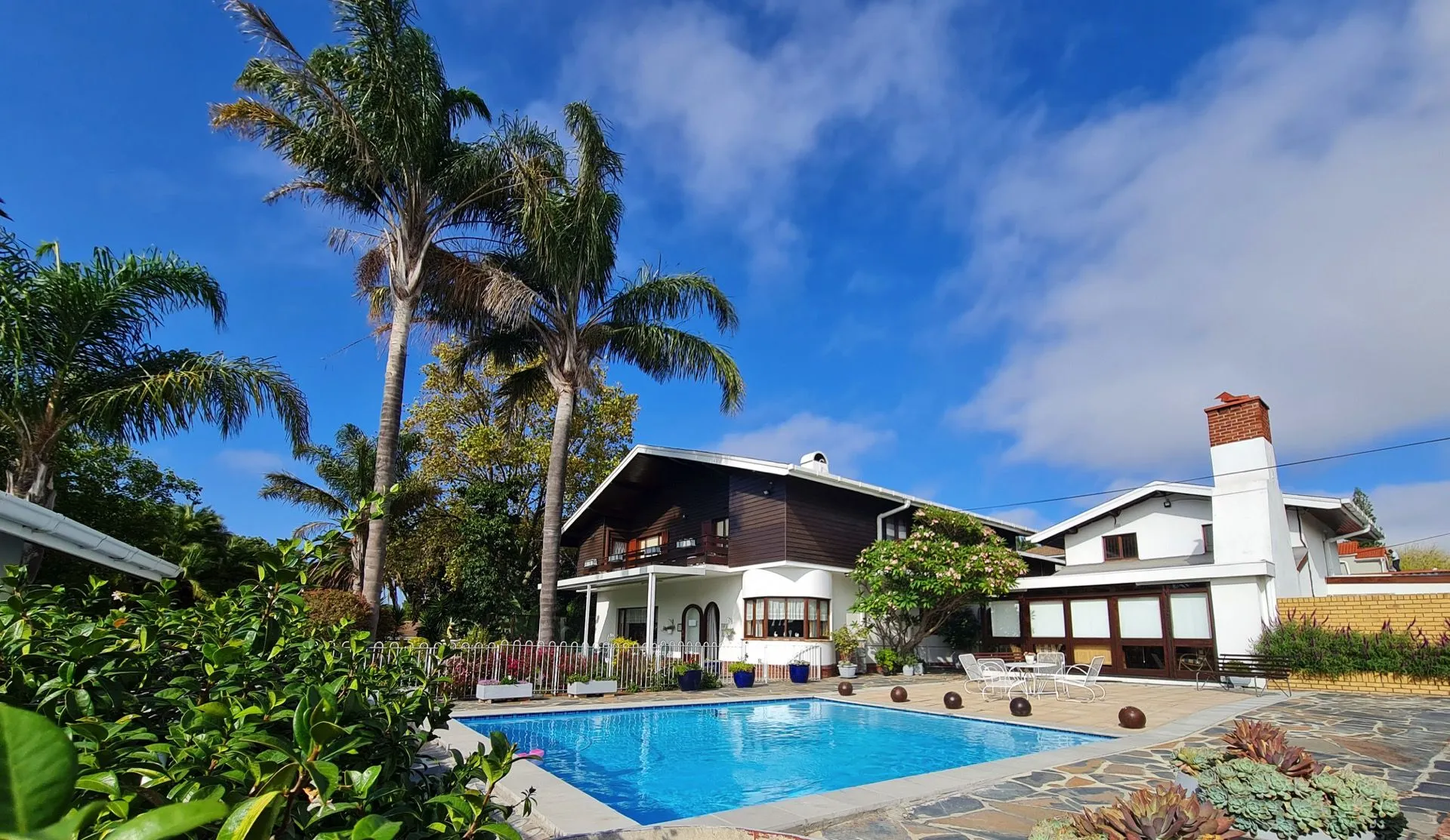 Large house with pool palm trees and clear blue sky in the background