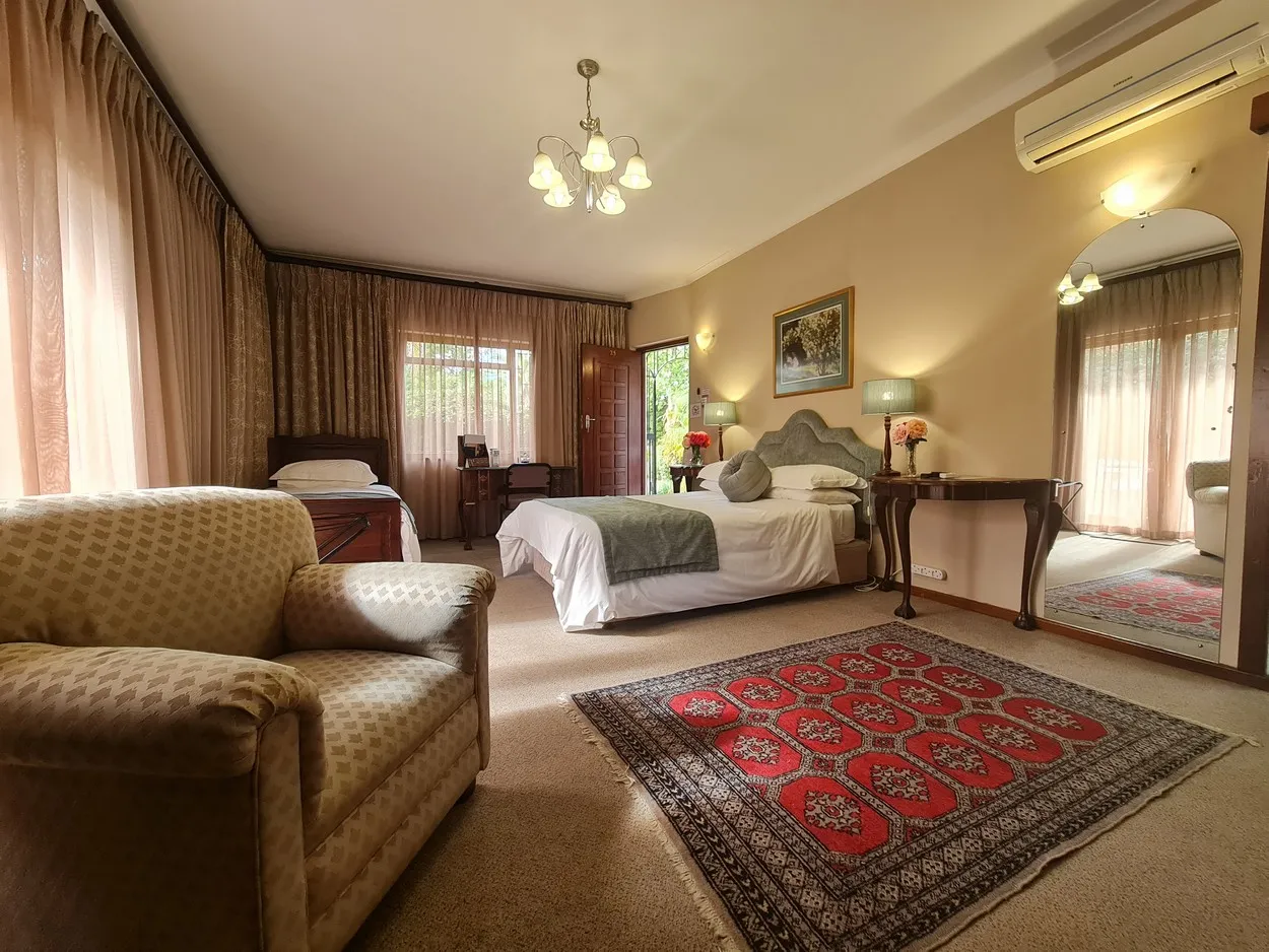 Cozy bedroom with a bed armchair and red patterned rug on beige carpet
