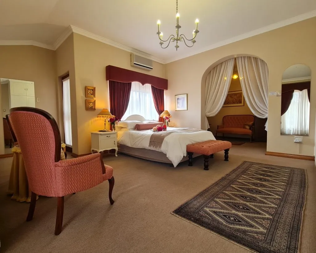 Elegant bedroom with large bed armchair and arched alcove with seating area