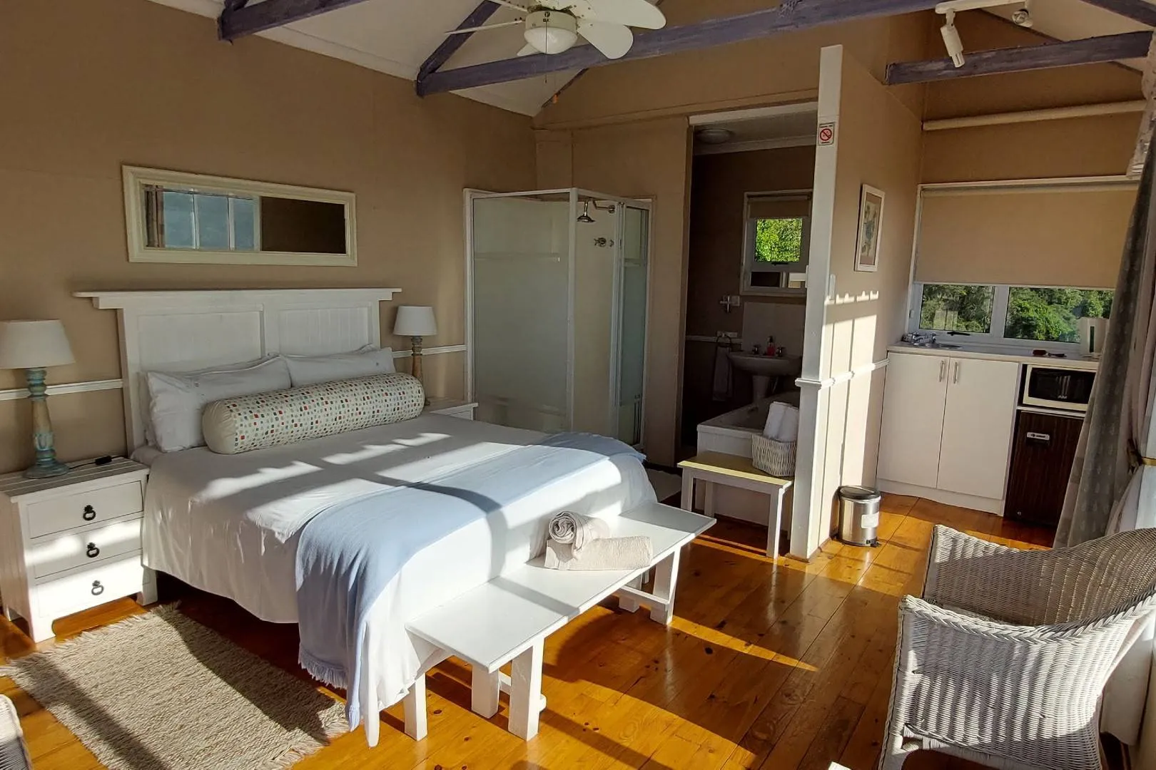 Bright bedroom with white bed wooden floor and open window view