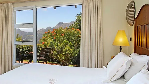 Bedroom with large window view of mountains and garden bed with white linens