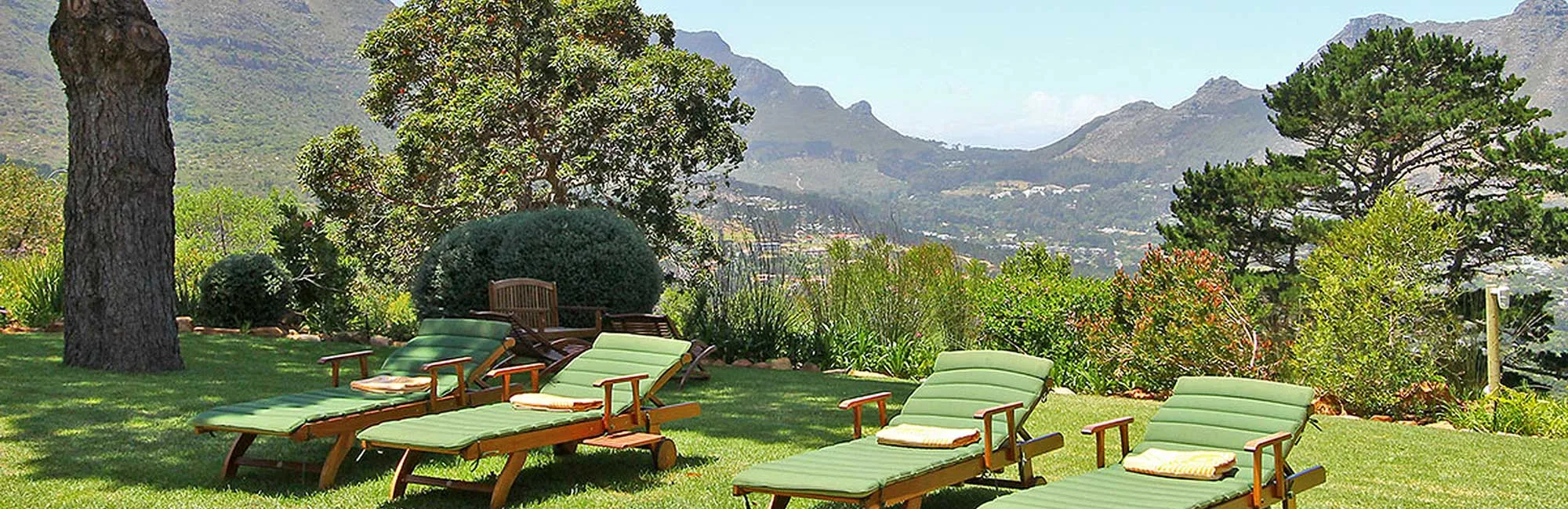Green lounge chairs on grass with a scenic mountain view in the background