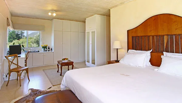 Bedroom with large bed desk and builtin wardrobes natural light from window