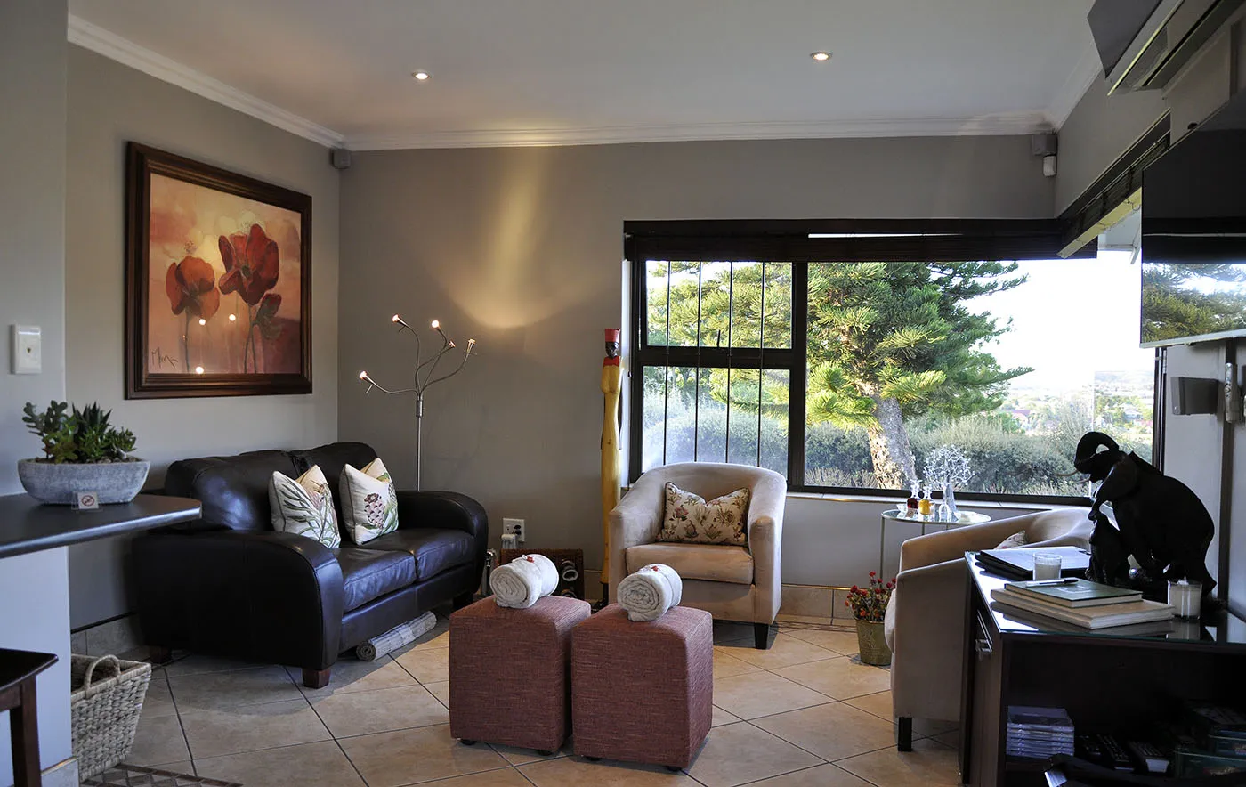 Modern living room with black leather sofa armchairs and large window view