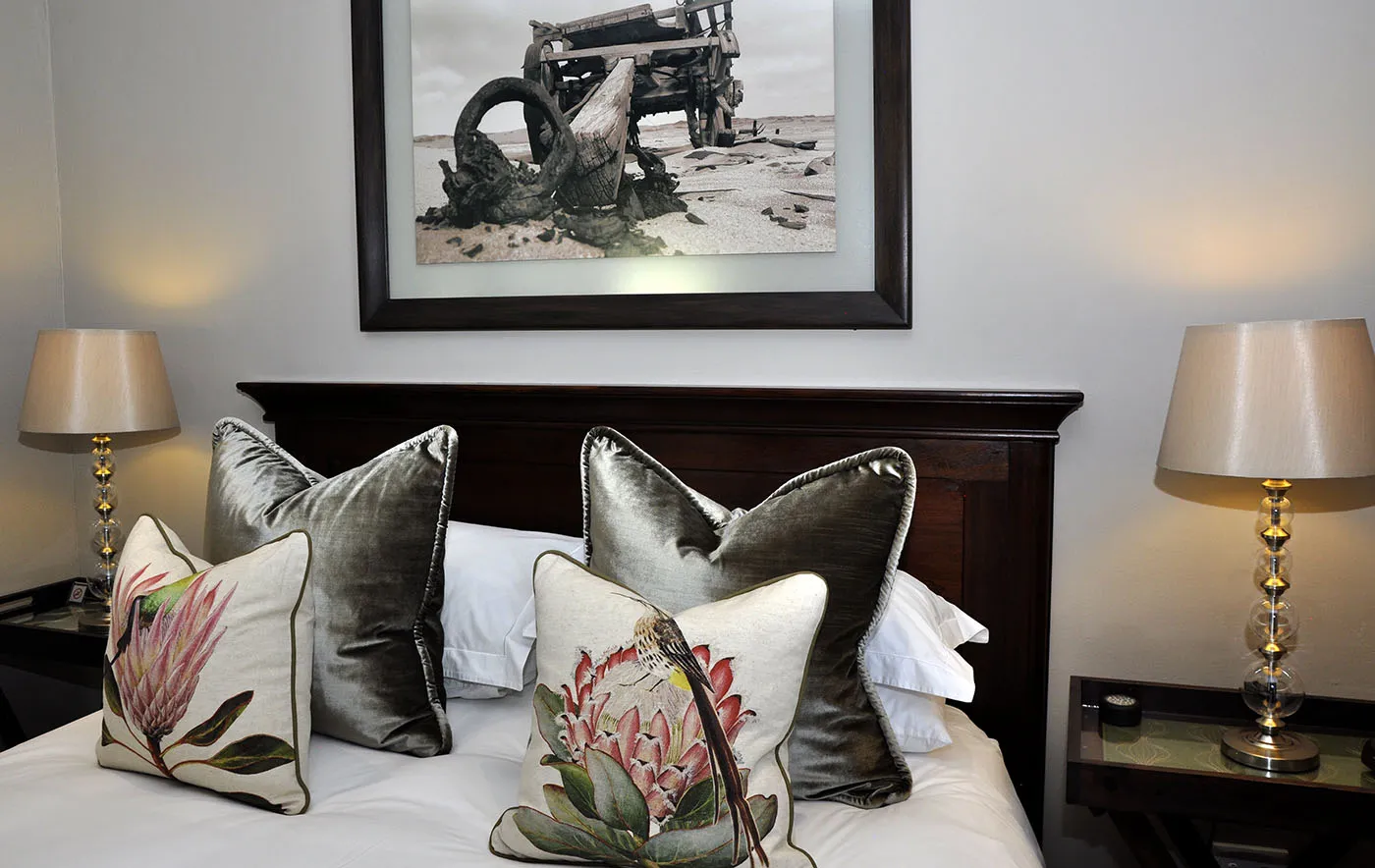 Bed with decorative pillows framed artwork above and bedside lamps in a bedroom
