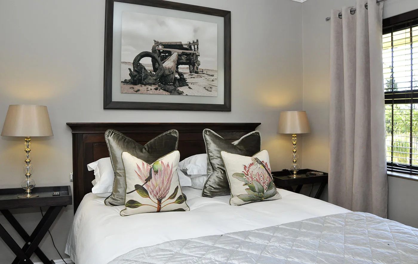 Cozy bedroom with two pillows bedside lamps and a framed picture above the bed