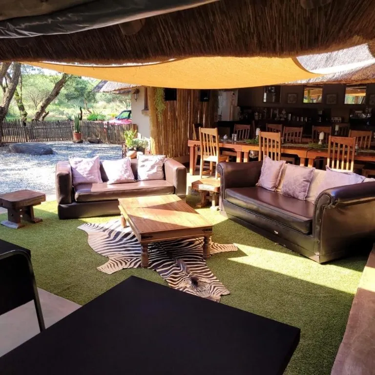 Cozy lounge area with sofas tables and a zebra skin rug on artificial grass