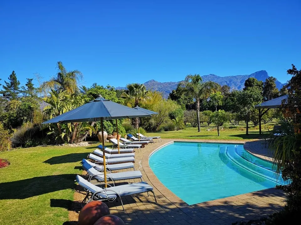 Swimming pool with lounge chairs and umbrellas in a lush garden setting