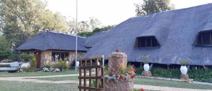 Traditional thatchedroof buildings with potted plants in a garden setting