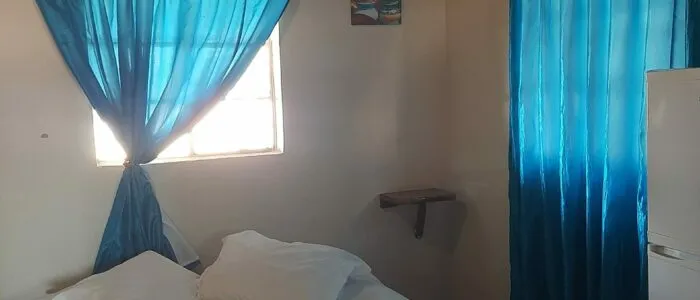 Bedroom with blue curtains bed window and small shelf on the wall