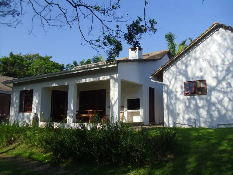 White house with a covered patio and garden in a sunny setting