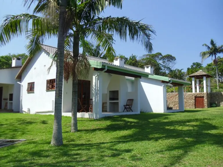 White house with green roof palm trees and grassy yard under blue sky