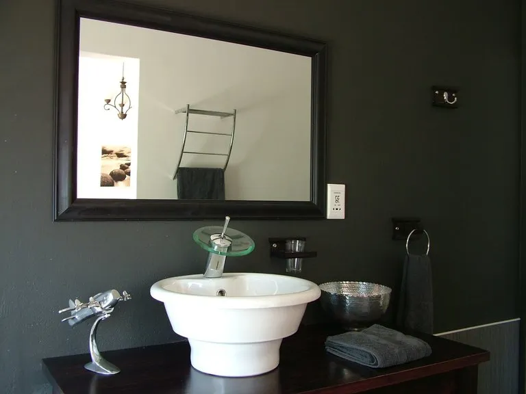 Modern bathroom sink with mirror towel and decorative items on a dark vanity