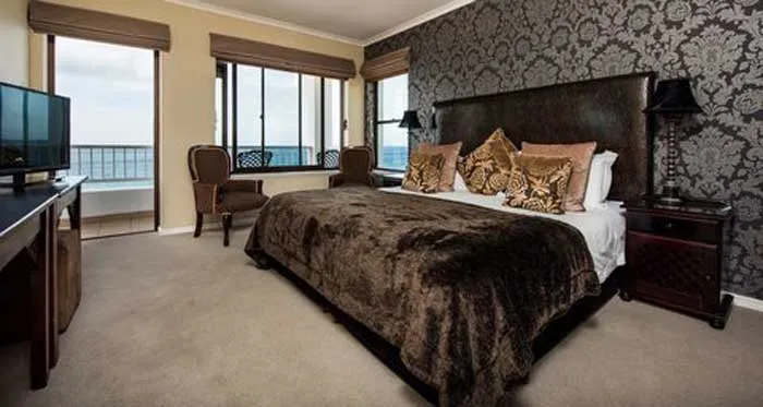 Luxury bedroom with large bed ocean view and ornate wallpaper