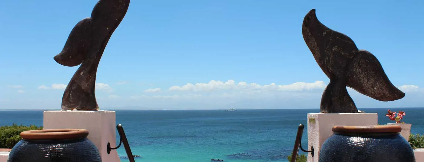 Two whale tail sculptures overlooking the ocean on a sunny day