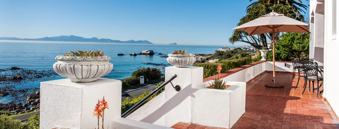 Ocean view from a patio with potted plants umbrella and seating area