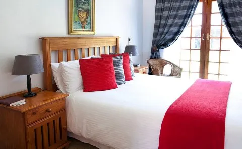 Cozy bedroom with a neatly made bed wooden furniture and large windows