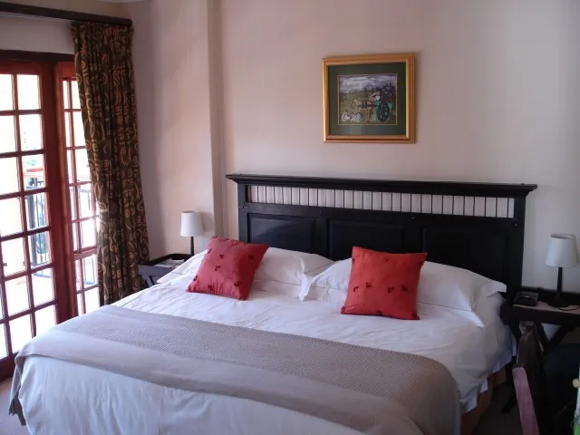 Neatly made bed in a bedroom with wooden headboard and red pillows