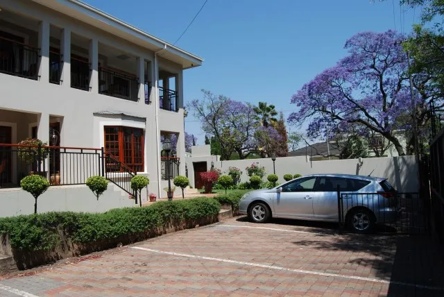 Modern twostory house with a car parked in the driveway surrounded by greenery
