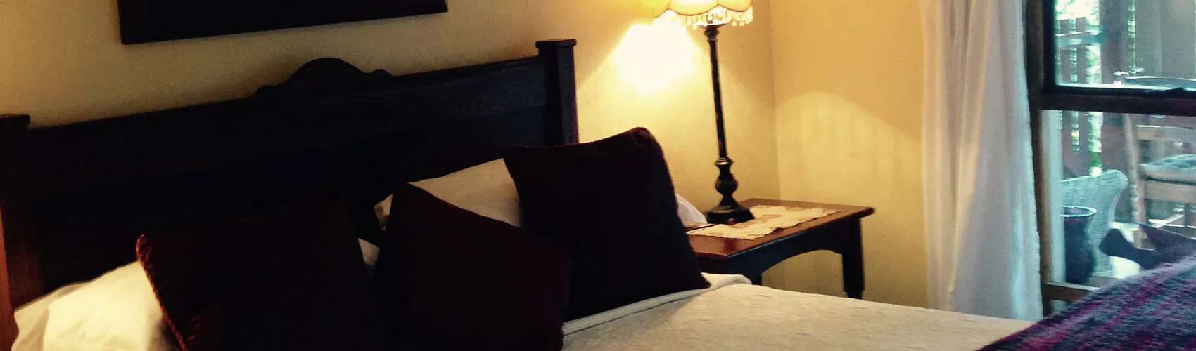 Bedroom with a bed pillows bedside table lamp and window with curtains