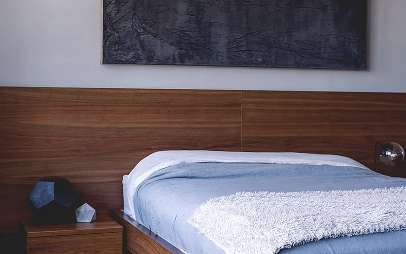 Modern bedroom with wooden headboard blue bedding and abstract wall art
