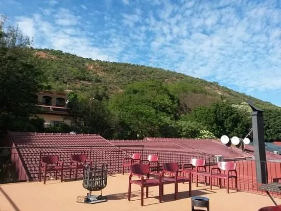 Red chairs on a rooftop with a scenic view of green hills