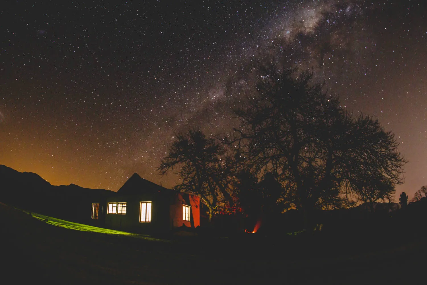 House under a starry night sky with the Milky Way visible in the background