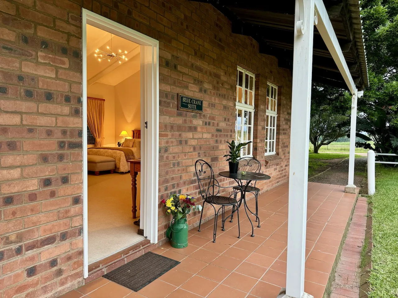 Brick building entrance with open door potted plant and outdoor seating area