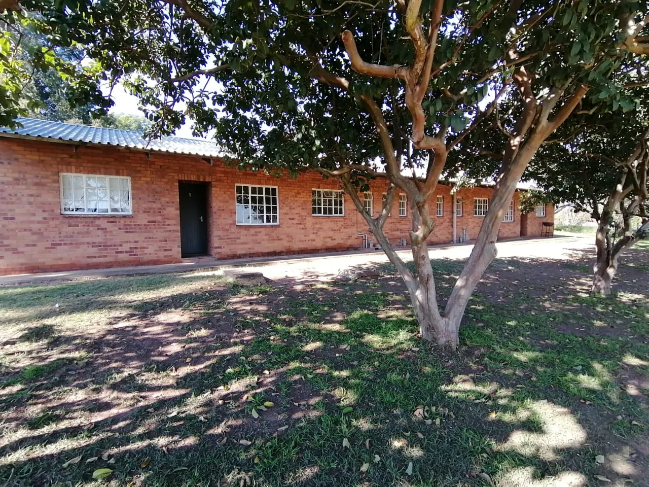 Singlestory brick building with trees in front grassy area and pathway