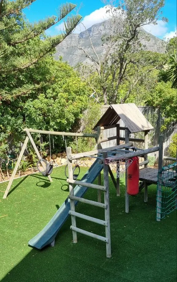 Wooden play structure with slide swings and climbing net in a garden