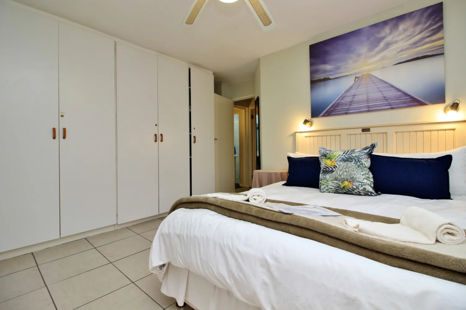 Modern bedroom with large bed white wardrobes and a ceiling fan