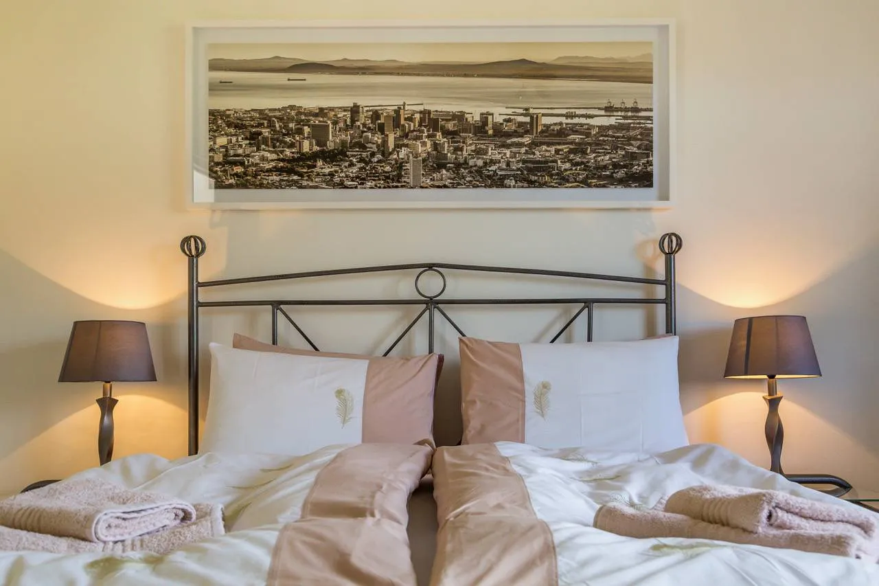 A bed with two pillows and a cityscape picture above it