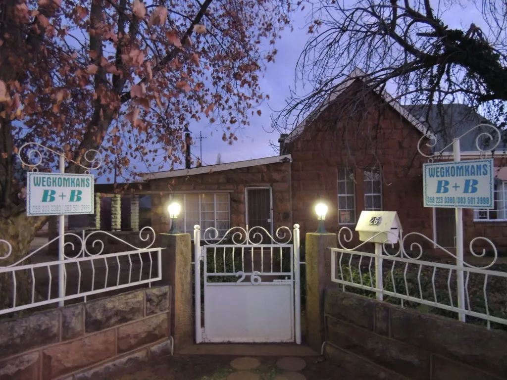 House with BB signs white gate and autumn trees at dusk