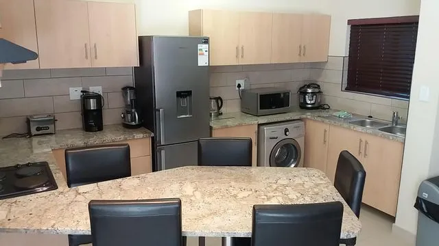 Modern kitchen with wooden cabinets black chairs and various appliances