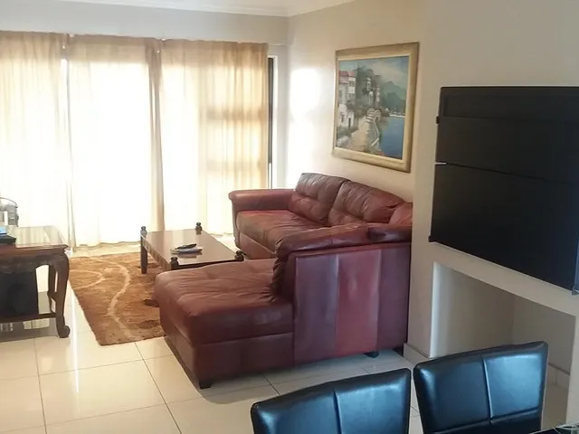 Red leather sofa in a living room with large windows and a painting