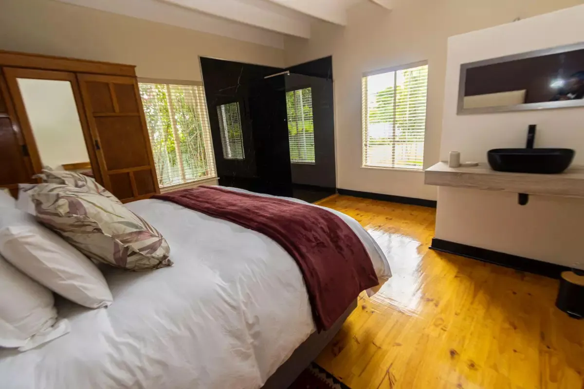 Modern bedroom with wooden floor large bed and open bathroom area